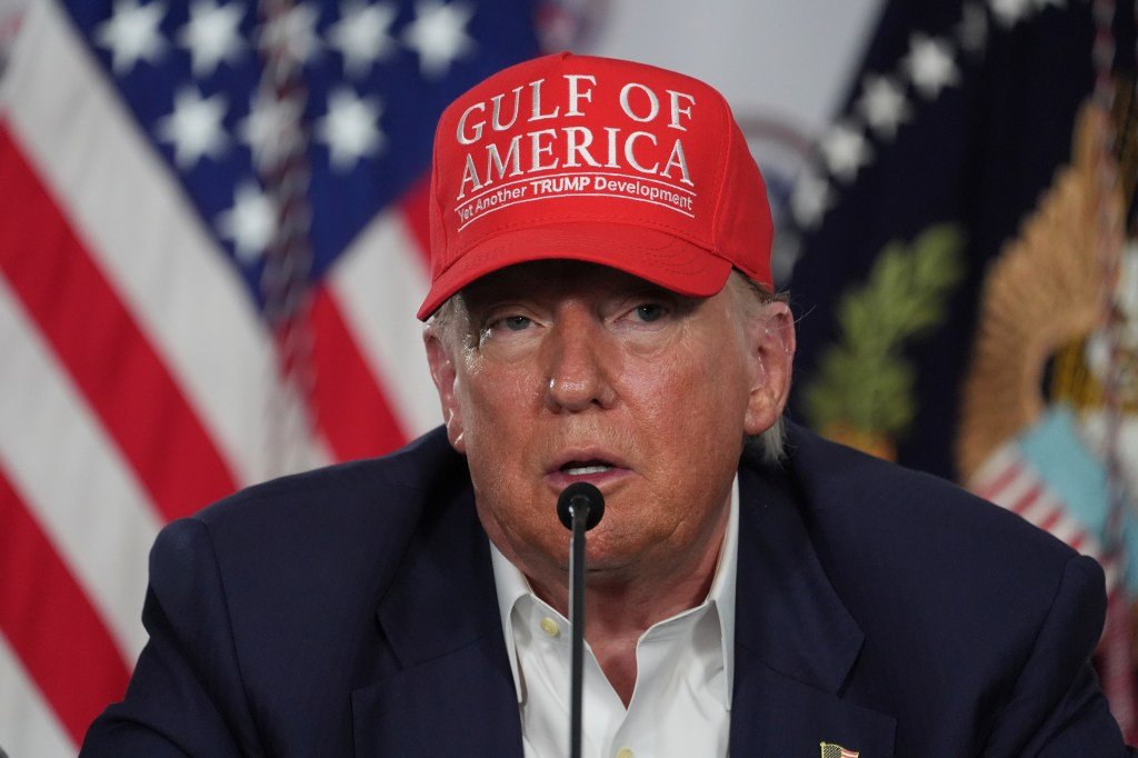 Donald Trump wearing a red hat that says "Gulf of America, Yet Another Trump Development".